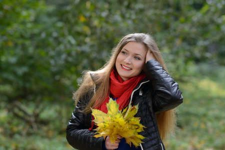 Young woman with autumn leaves in hand and garden backgroundの写真素材