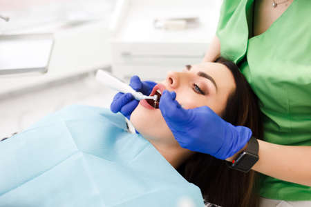 Young beautiful woman treats teeth at the dentist cabinet. Dental treatment processの写真素材