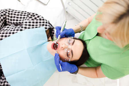 Young beautiful woman treats teeth at the dentist cabinet. Dental treatment processの写真素材