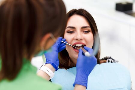 Dentist doctor drills teeth with a drill to a young woman. Girl at the dentist's appointmentの写真素材