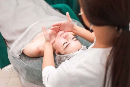 Doctor beautician doing cosmetological massage of the chin for her patientの写真素材