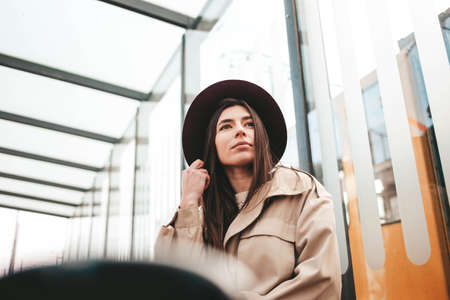 Pensive woman in hat and coat sitting at the bus stopの写真素材