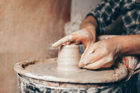 Man forms a white clay product on a pottery wheel closeupの写真素材