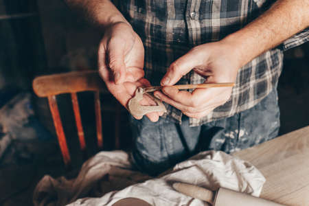 Ceramic master smears a heart cut out of clay with a brushの写真素材