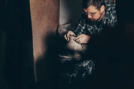Man works on the potter's wheel creating a jug of clayの写真素材