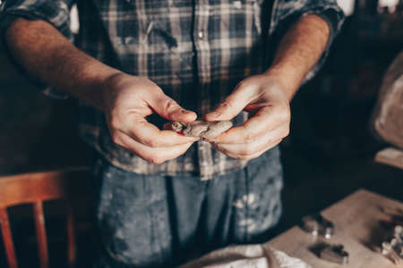 Potter kneads a piece of clay in his handの写真素材