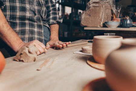 Male potter rolls clay to create a cup
