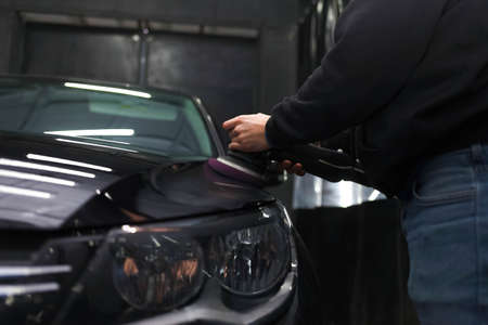 Worker polishes a car's paintwork with a carの写真素材