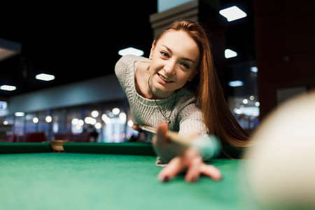 Young smiling woman plays billiards in billiards clubの写真素材
