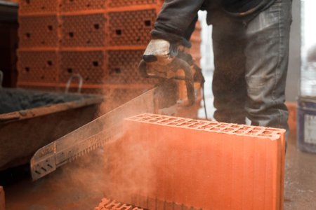 Construction worker cuts a brick with a saw