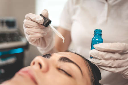 Doctor beautician applies oil to the skin of the faceの写真素材