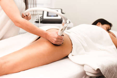 Doctor cosmetologist doing roller massage with apparatus close upの写真素材