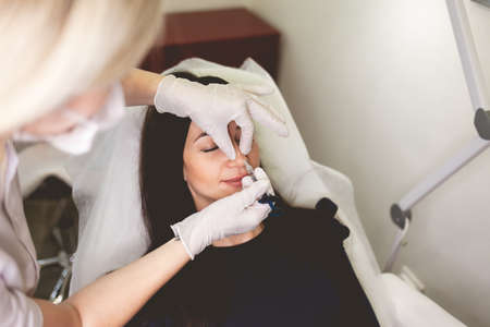 Woman make injection of beauty in the nose. Botox procedure in beauty salonの写真素材