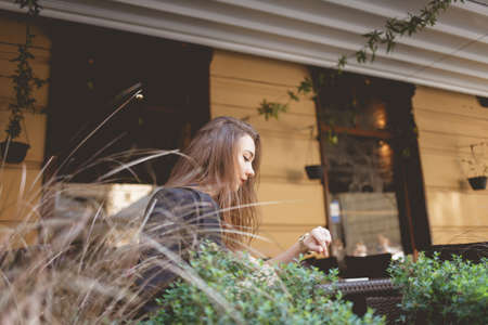 lonely lady looks at the time while sitting at a restaurant tableの写真素材