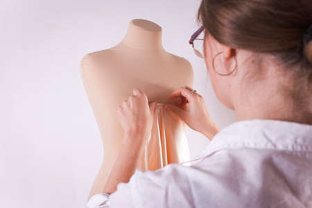Seamstress cuts fabric with big scissors on a mannequin.の写真素材
