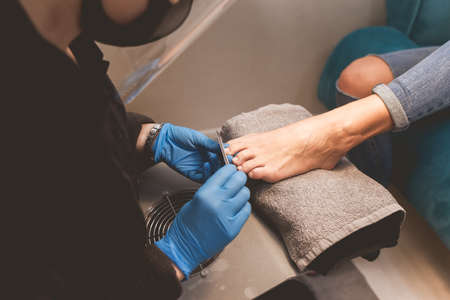 Pedicure master files nails with a nail file for subsequent application of varnishの写真素材