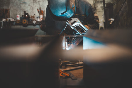 Worker in a welder mask works in a workshop for welding iron. Man makes iron products. Guy works...