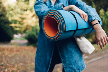 Girl with a sports mat in hands hurries to yoga class. Yoga mat closeup concept