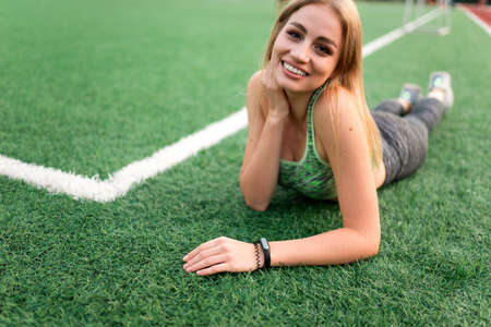 Fitness girl lying on the grass of a soccer fieldの写真素材