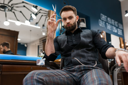 Handsome male hairdresser with scissors in hands