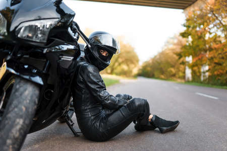 Biker girl in sits leaning on a motorcycleの写真素材