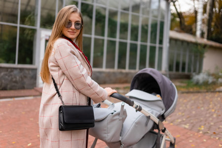 Portrait of stylish mother with baby stroller for a walk