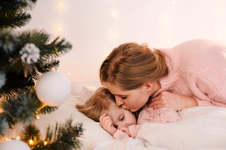 Mom kisses sleeping daughter on christmas morningの写真素材