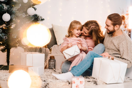 Happy family gives their daughter Christmas gifts. Little girl rejoices giftboxの写真素材