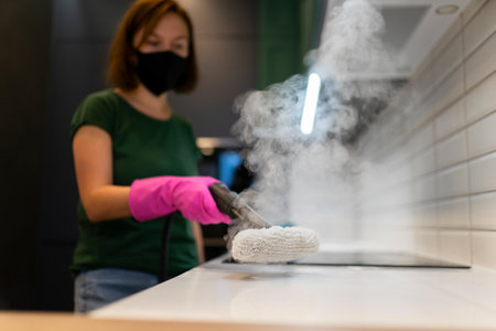 Woman cleaning kitchen furniture with steam cleanerの写真素材