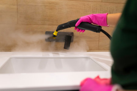 Cleaning the faucet from fungi and dirt with steam cleaner. Bathroom cleaning processの写真素材