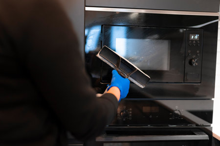 Woman washing the glass of the oven with a glass cleanerの写真素材