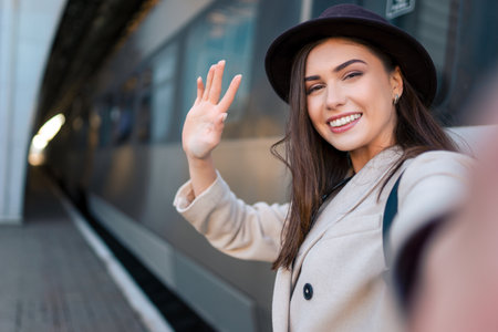 Pretty girl tourist takes selfie at the railway station against the background of the locomotive. Girl talking on video callの写真素材