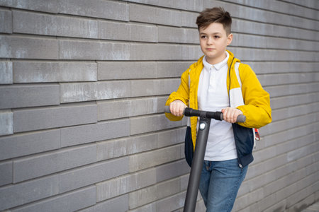 Handsome teenager rides on electric scooter down the city streetの写真素材