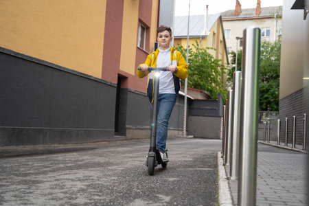 Handsome teenager rides on electric scooter down the city streetの写真素材