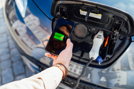 Smartphone app shows charging status of the electric car battery. Electro transport concept