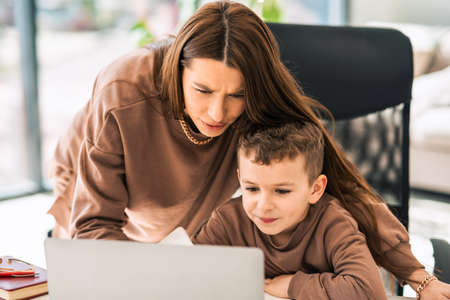 Mother helps her little son with online homework on laptop. Distance educationの写真素材