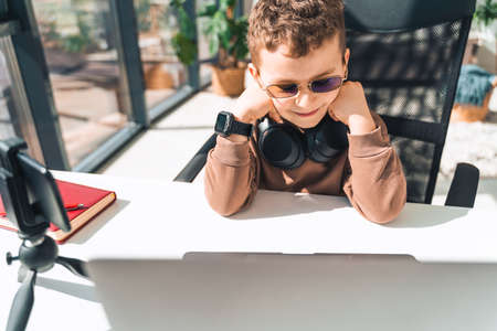 Schoolboy watches online video lessons on laptop. Studying during an epidemicの写真素材