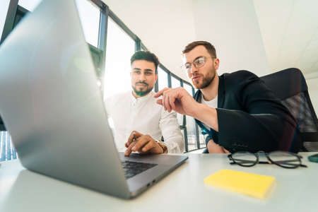 Two handsome business men use laptop to workの写真素材