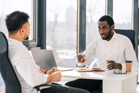 Business colleagues talking while sitting at the table in the officeの写真素材