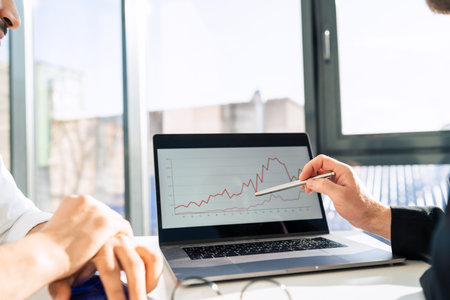 Two businessmen at laptop are watching chart of the company's income growth