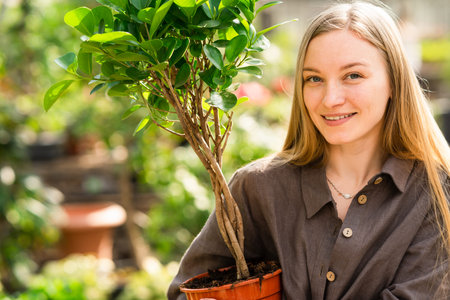 Close-up portrait of pretty greenhouse worker with plant
