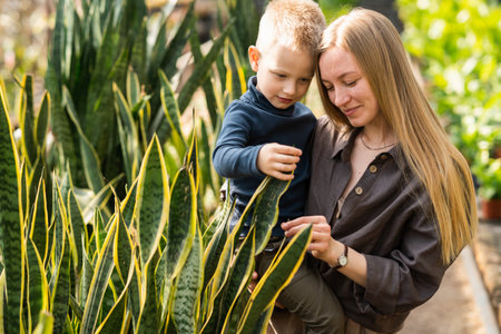 Loving mother with her son in her arms in a greenhouseの写真素材