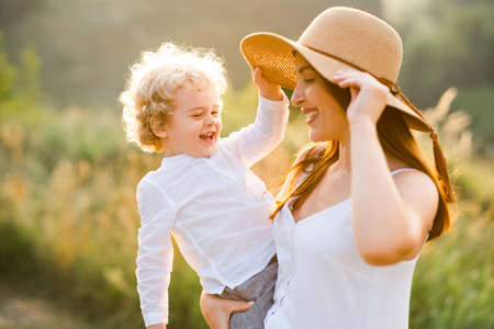 Pretty woman in straw hat holds a boy in her armsの写真素材