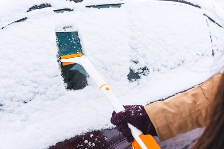 Woman cleans the car of snowの写真素材
