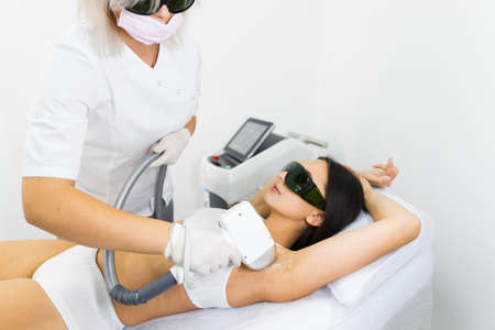 Woman in white underwear doing laser hair removal on armpits in epilation salonの写真素材