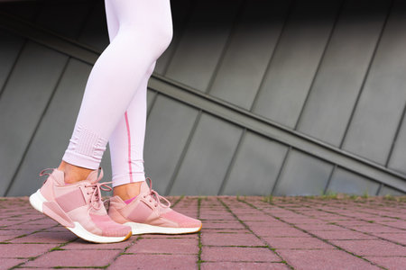 Legs of sportswoman in pink sneakers