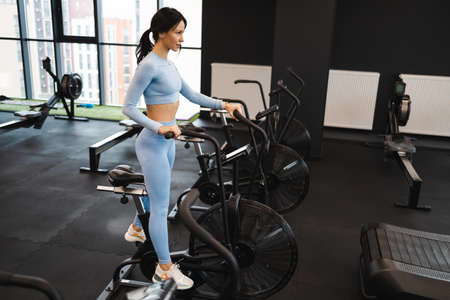Sportswoman training on exercise bike in gymの写真素材