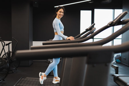 Happy fitness woman walks on a treadmill
