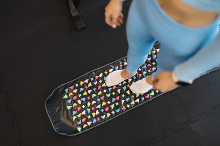 Acupuncture points of the foot stimulation. Woman stand on orthopedic foot massage mat. Massage rug...
