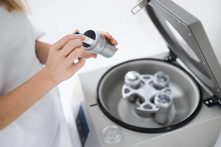Cosmetologist puts tube of blood in centrifuge. Plasmolifting procedure. Preparation of blood for injectionsの写真素材